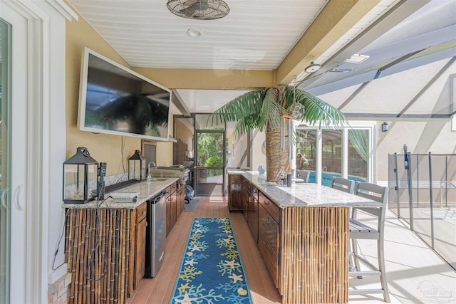 view of patio with a lanai, ceiling fan, wine cooler, and a wet bar