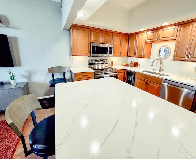 kitchen featuring brown cabinetry, ornamental molding, stainless steel appliances, and a sink