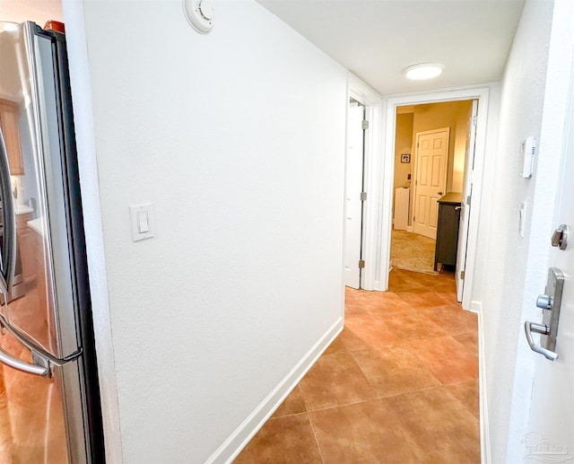 hall with light tile patterned flooring and baseboards