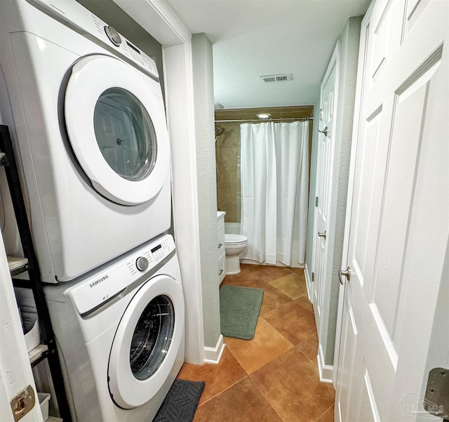 clothes washing area with laundry area, stacked washer and dryer, light tile patterned floors, and visible vents