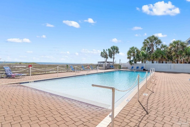 community pool with a patio area and fence