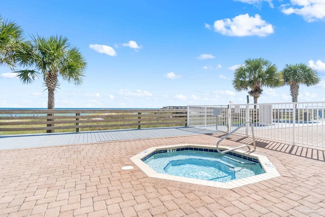 view of swimming pool with fence and a hot tub