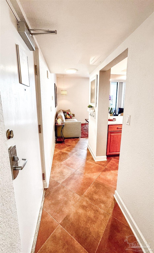 hall featuring baseboards and light tile patterned flooring