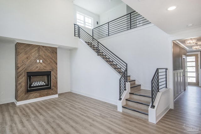 staircase featuring an inviting chandelier, a large fireplace, a healthy amount of sunlight, and wood-type flooring