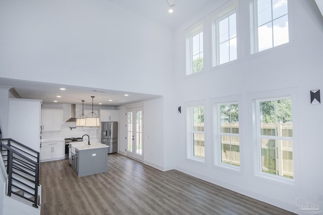 kitchen featuring pendant lighting, stainless steel appliances, a center island with sink, and white cabinets