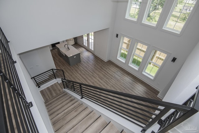 staircase with a high ceiling, plenty of natural light, hardwood / wood-style floors, and french doors