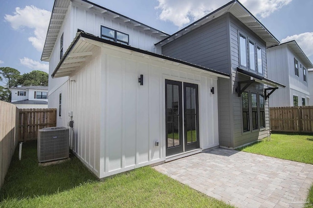 rear view of property with a lawn, central AC, and a patio area