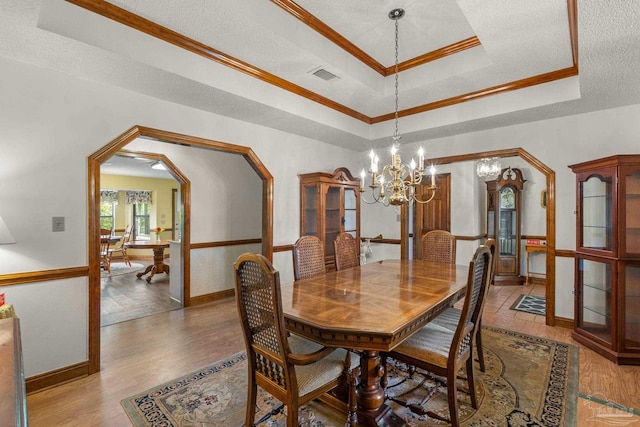 5816 Forest Ridge Dr, Pensacola, FL 32526 - dining space with a raised ceiling, a chandelier, arched walkways, light wood-style floors, and crown molding