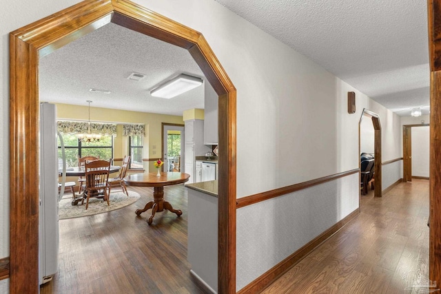 5816 Forest Ridge Dr, Pensacola, FL 32526 - hall featuring a textured ceiling, dark wood-style flooring, a chandelier, arched walkways, and baseboards