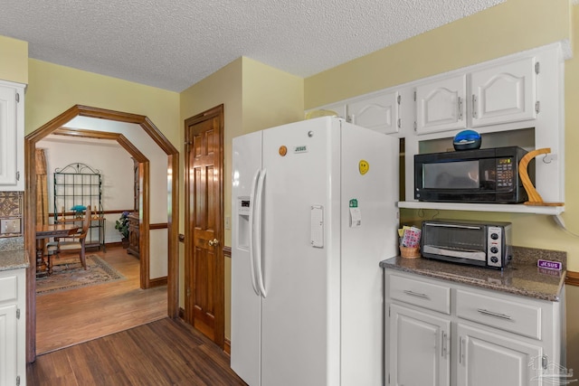 5816 Forest Ridge Dr, Pensacola, FL 32526 - kitchen with white fridge with ice dispenser, black microwave, dark wood-style flooring, white cabinetry, and a textured ceiling