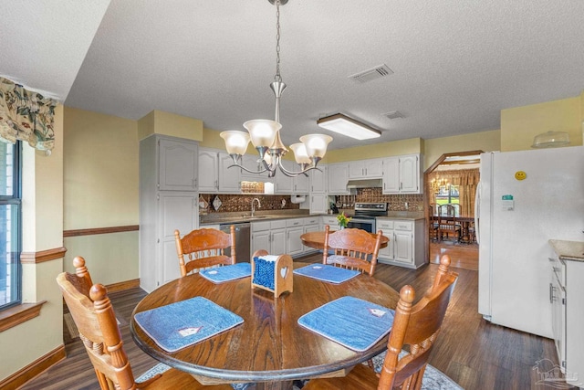 5816 Forest Ridge Dr, Pensacola, FL 32526 - dining space featuring a chandelier, dark wood-style flooring, a textured ceiling, and baseboards