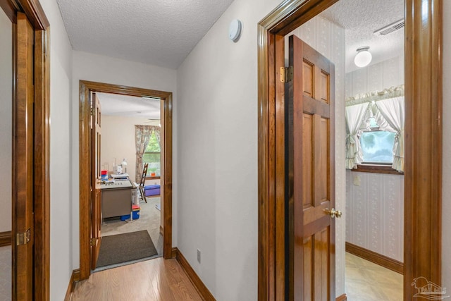 5816 Forest Ridge Dr, Pensacola, FL 32526 - corridor with a textured ceiling, wallpapered walls, light wood-style flooring, and baseboards