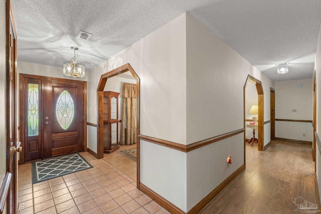 5816 Forest Ridge Dr, Pensacola, FL 32526 - foyer entrance with a textured ceiling, arched walkways, baseboards, a chandelier, and light wood-style flooring