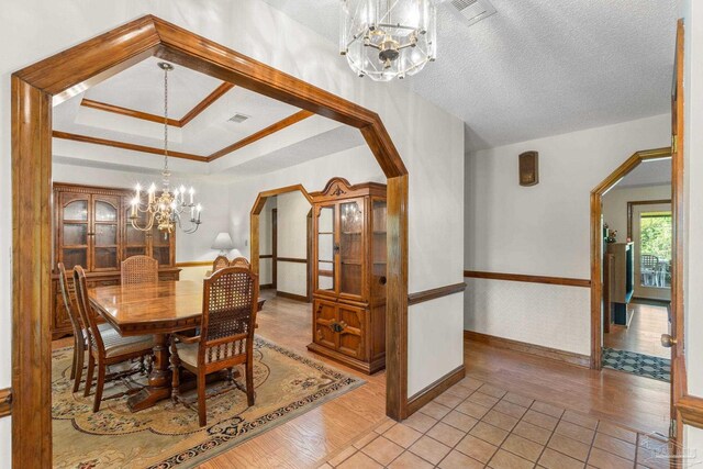 5816 Forest Ridge Dr, Pensacola, FL 32526 - dining room with a chandelier, arched walkways, light wood-style flooring, baseboards, and a textured ceiling