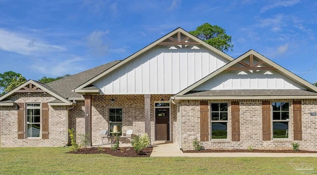 craftsman house featuring board and batten siding, a front yard, roof with shingles, and brick siding