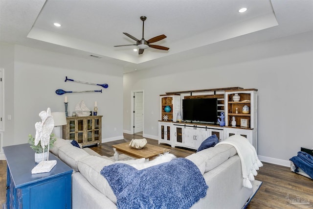 living room with a raised ceiling, visible vents, and dark wood-style flooring