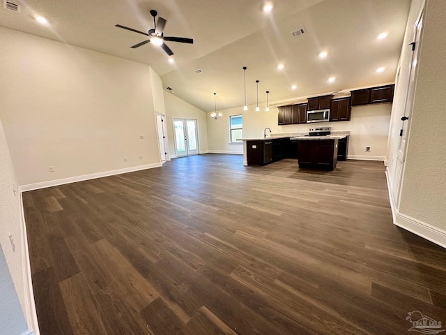 kitchen with open floor plan, an island with sink, appliances with stainless steel finishes, dark wood finished floors, and lofted ceiling