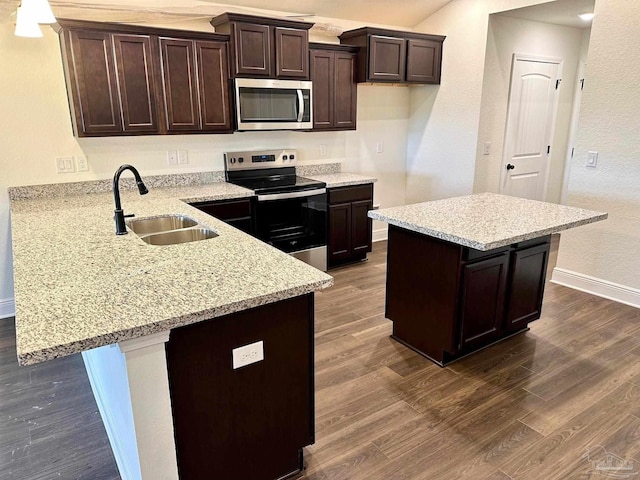 kitchen featuring stainless steel appliances, a sink, dark wood-style floors, dark brown cabinetry, and baseboards