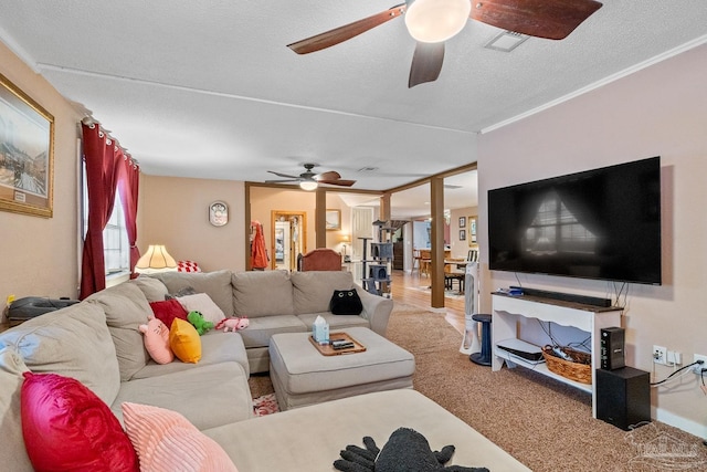 living room featuring carpet floors, visible vents, a textured ceiling, and a ceiling fan