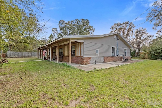 view of property exterior featuring brick siding, a yard, board and batten siding, a patio area, and fence