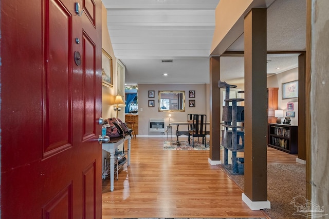 foyer featuring heating unit, light wood finished floors, baseboards, and visible vents