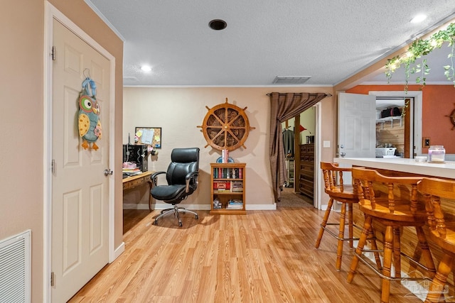 office area featuring crown molding, visible vents, light wood-style floors, a bar, and baseboards