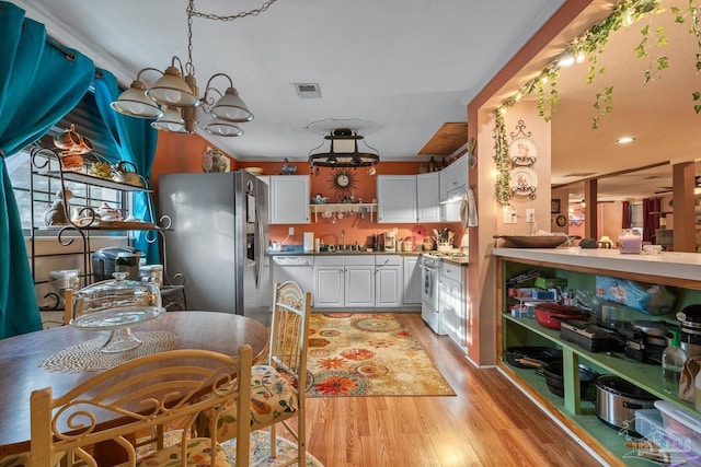 kitchen with stainless steel appliances, a sink, visible vents, light wood-style floors, and white cabinets