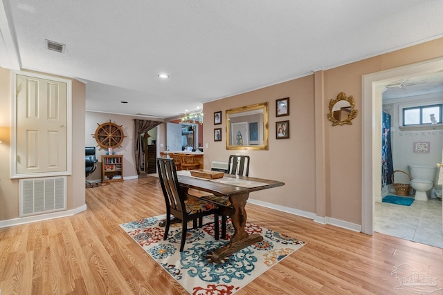 dining room with light wood-style flooring, visible vents, and baseboards