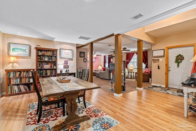 dining room featuring light wood-style flooring, visible vents, and a textured ceiling