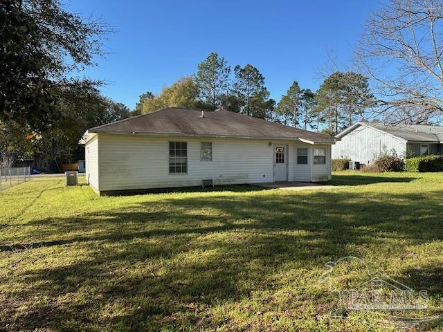 back of house with cooling unit and a lawn