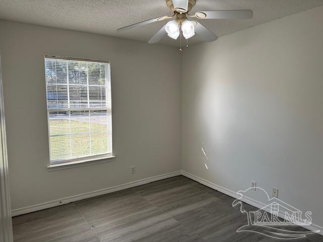 spare room featuring a wealth of natural light, baseboards, a textured ceiling, and wood finished floors