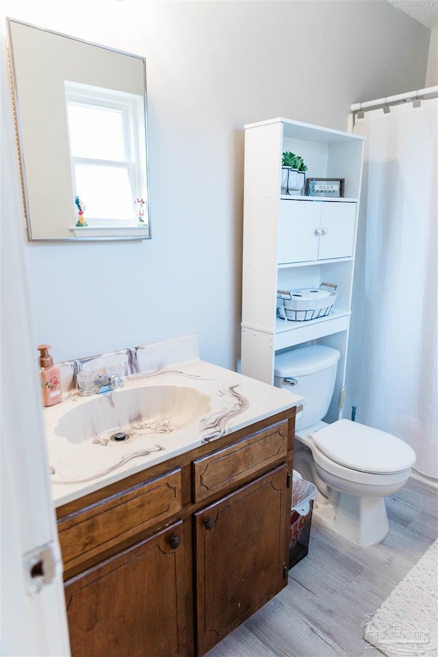 full bath featuring wood finished floors, vanity, toilet, and curtained shower