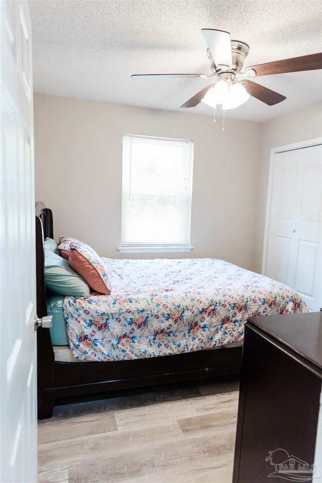 bedroom with light wood finished floors, ceiling fan, and a textured ceiling