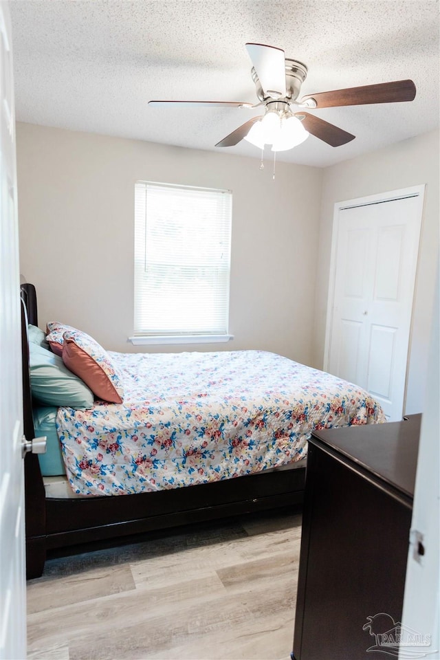 bedroom featuring light wood-type flooring, ceiling fan, and a textured ceiling