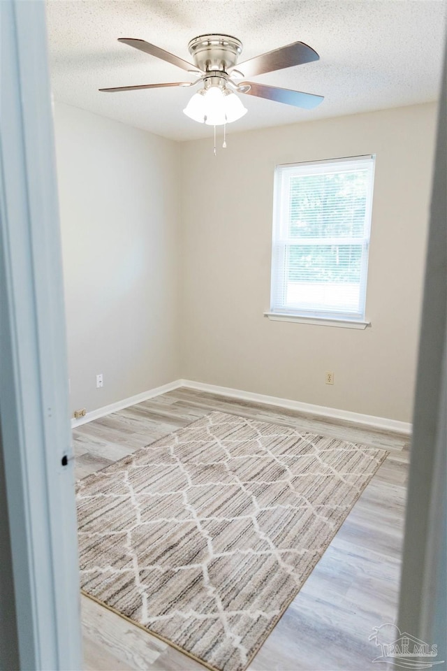 empty room with a ceiling fan, baseboards, wood finished floors, and a textured ceiling
