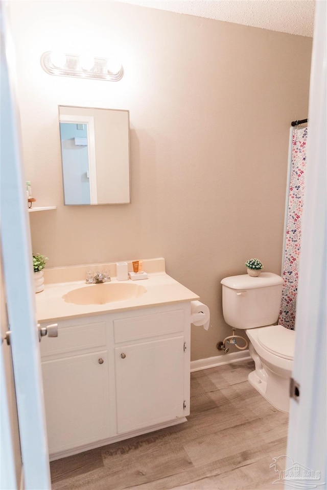 full bathroom featuring toilet, vanity, wood finished floors, and baseboards