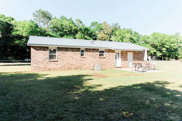 rear view of house featuring brick siding, a patio, metal roof, and central AC