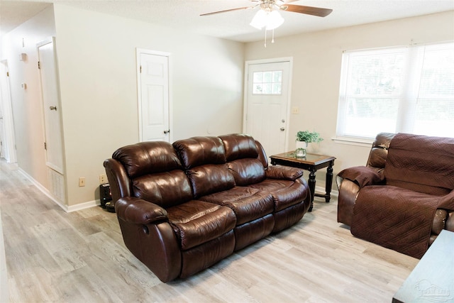 living area featuring light wood-style floors, ceiling fan, and baseboards