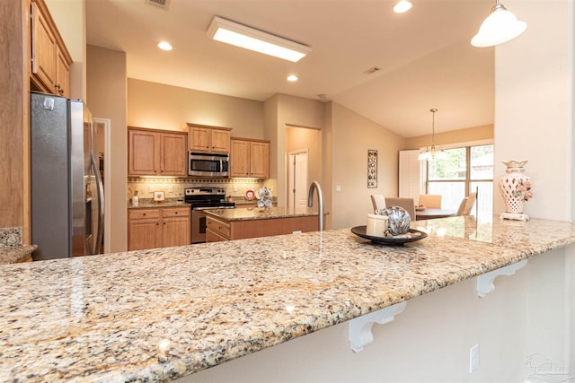 2255 Reed Ridge Ct, Navarre, FL 32566 - kitchen featuring vaulted ceiling, a peninsula, stainless steel appliances, and light stone counters