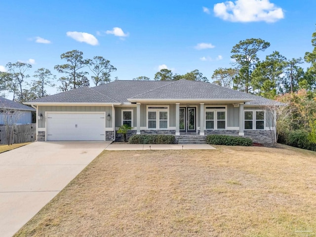 view of front of house featuring covered porch, a front yard, and a garage