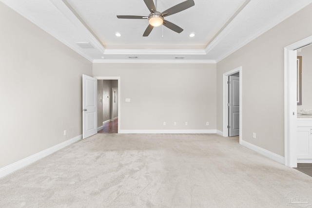 unfurnished bedroom with a tray ceiling, ensuite bathroom, crown molding, and ceiling fan