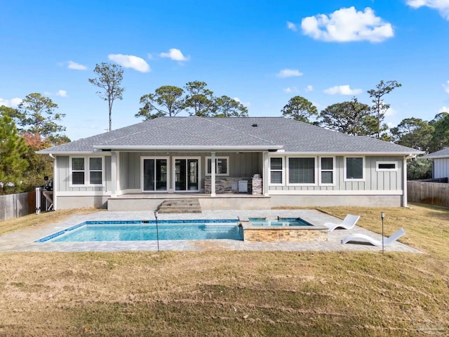 rear view of property with a swimming pool with hot tub, a patio area, and a lawn