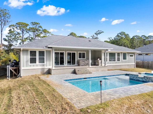 rear view of house with a lawn, a patio, and a pool with hot tub