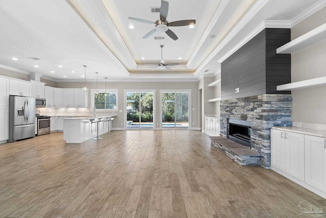 unfurnished living room with a fireplace, built in shelves, light hardwood / wood-style floors, and ceiling fan