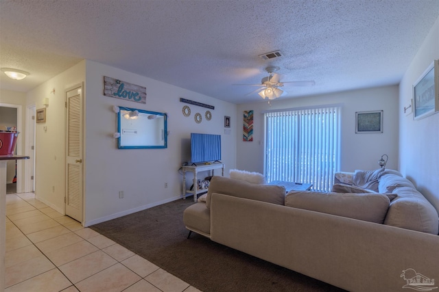 living room featuring ceiling fan, a textured ceiling, and light tile patterned floors