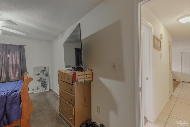 bedroom featuring light tile patterned floors, a textured ceiling, and ceiling fan