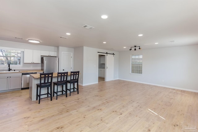 kitchen with sink, stainless steel appliances, a center island, a kitchen bar, and a barn door