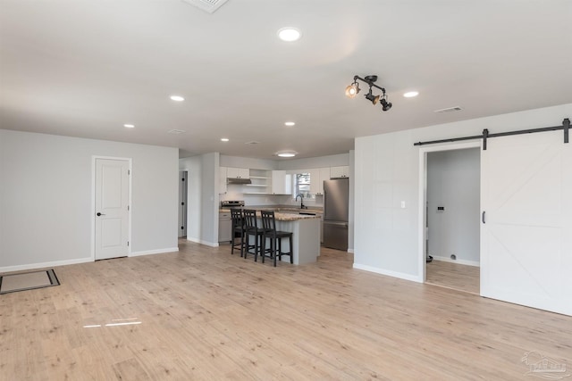 unfurnished living room featuring a barn door, sink, and light hardwood / wood-style floors