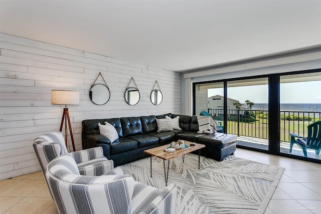 living room featuring wood walls, a water view, and light tile patterned flooring