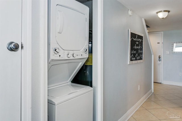 clothes washing area with light tile patterned floors and stacked washing maching and dryer